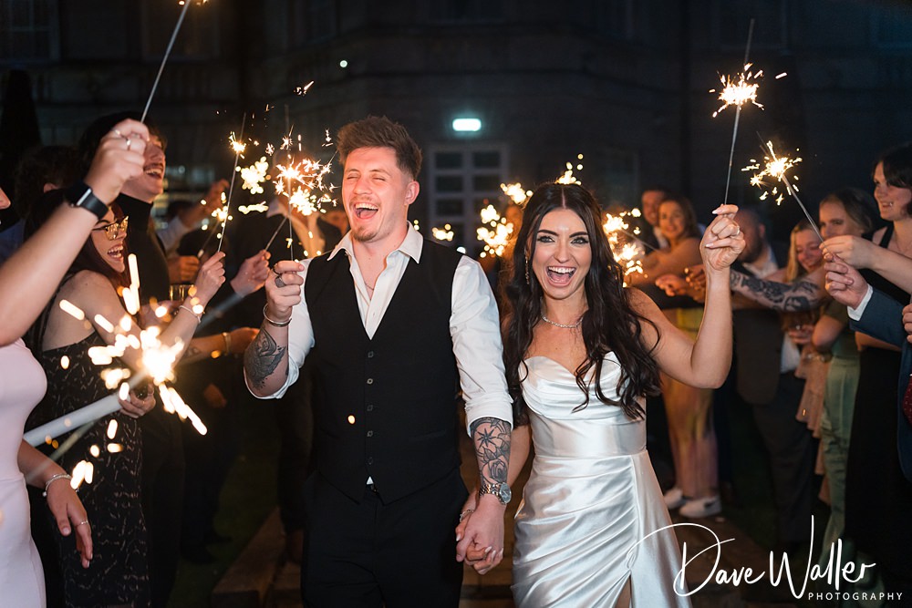 Couple celebrating with sparklers at wedding party.