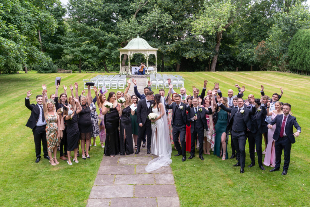 Outdoor wedding group photo with smiling guests