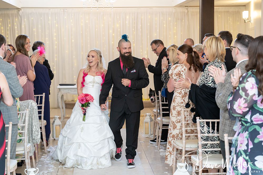 Bride and groom walking down the aisle, smiling.