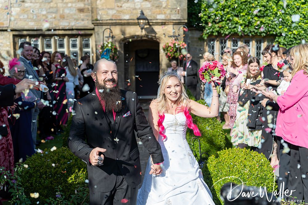 Newlyweds celebrate with guests, confetti, and bouquet.