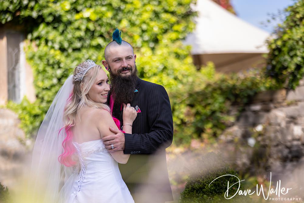 Couple posing in wedding attire outdoors.