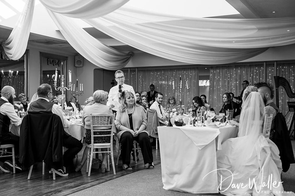 Wedding reception speech with seated guests listening attentively.