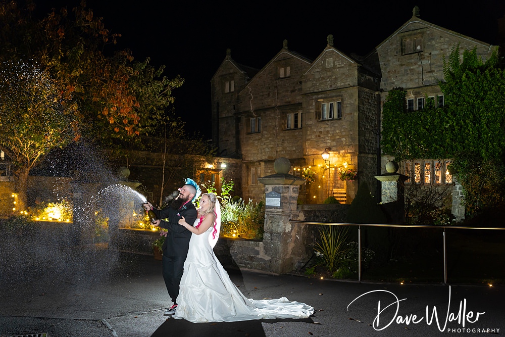 Wedding couple sprays champagne outside manor house