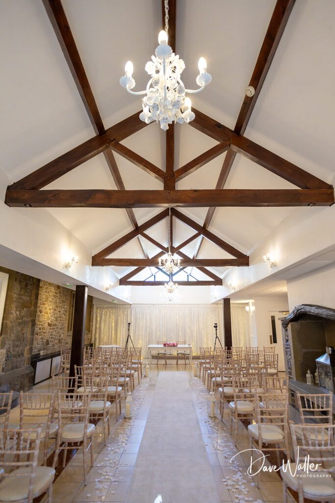 Elegant wedding venue with chandeliers and rows of chairs.