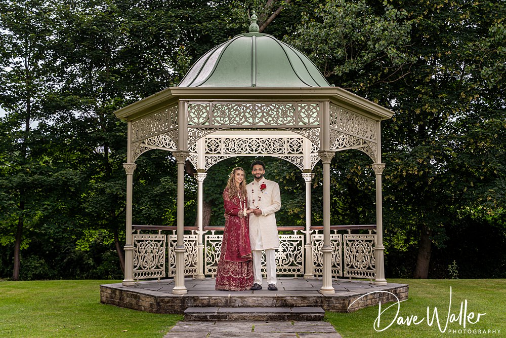 Couple standing in ornate garden gazebo.