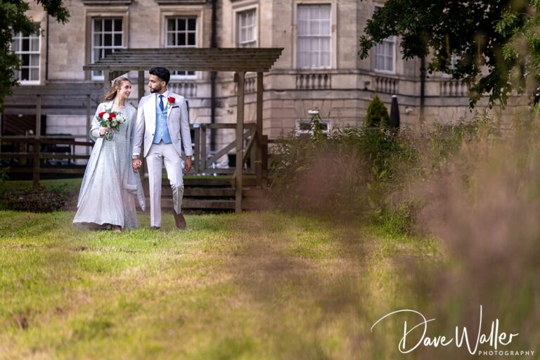 Couple walking outdoors at elegant wedding venue.