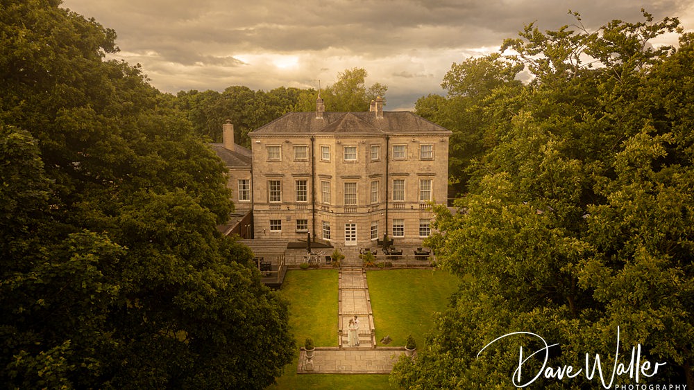 Historic mansion with garden and cloudy sky.