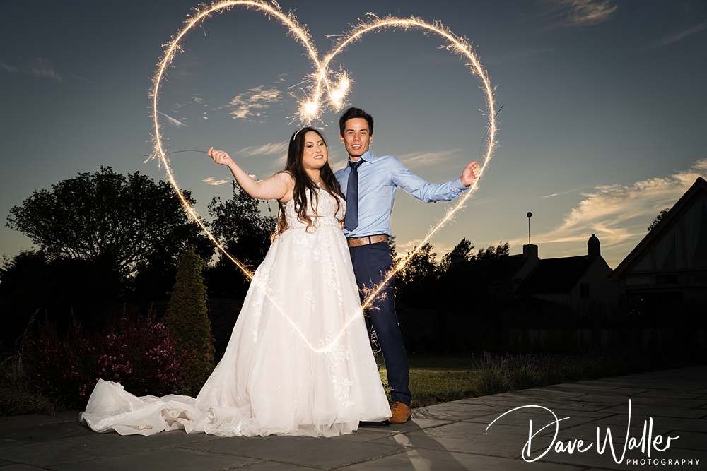 Bride and groom with heart-shaped sparkler effect.