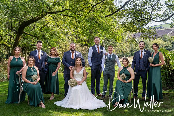 Outdoor wedding party with green dresses and suits.