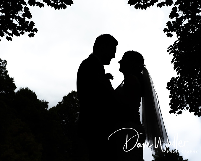Silhouette of couple under trees on wedding day.