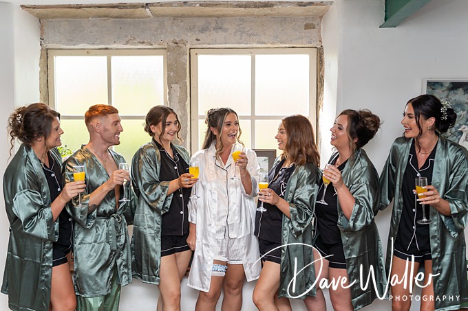 Group celebrating in robes with drinks near window.