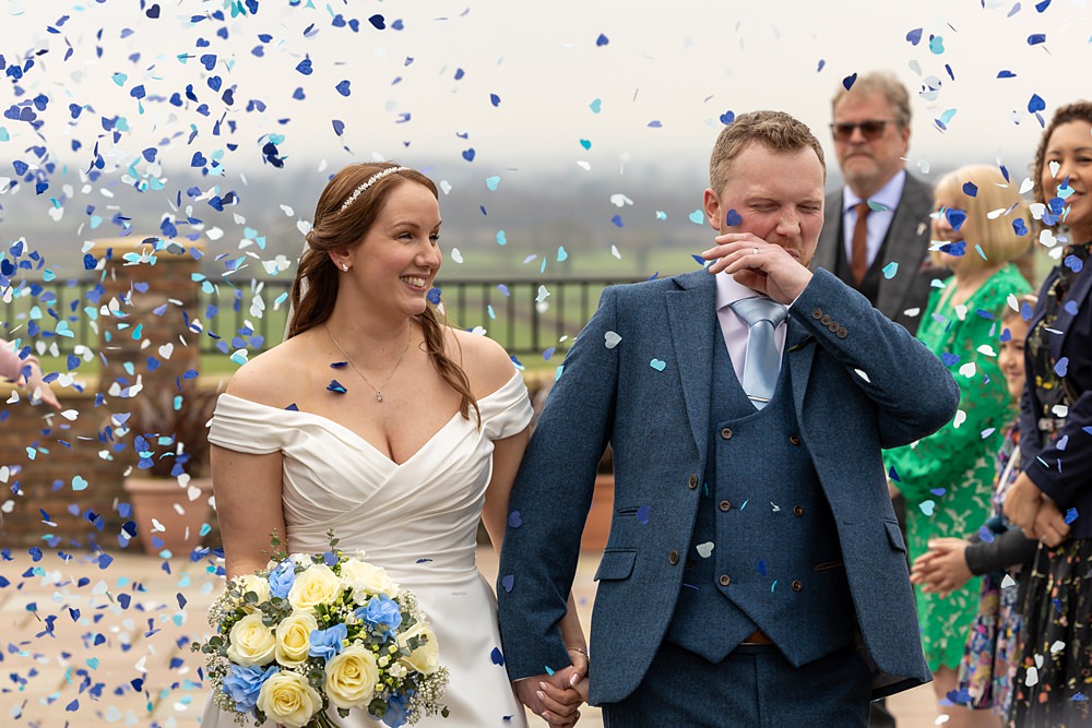 Bride and groom with confetti at wedding ceremony.