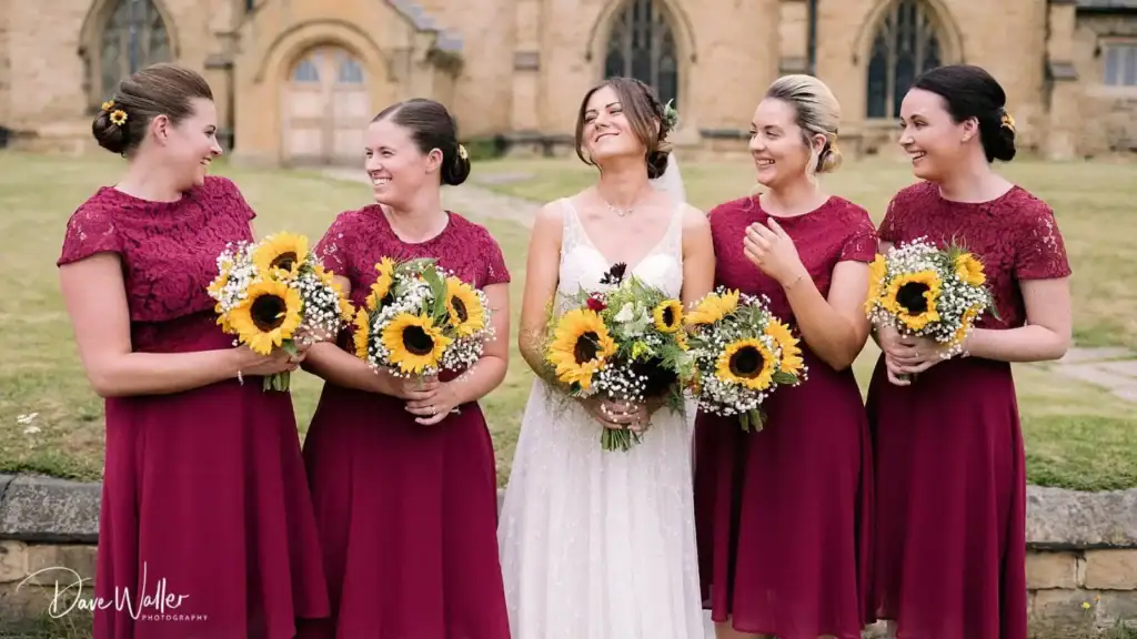 Bride with bridesmaids holding sunflower bouquets.