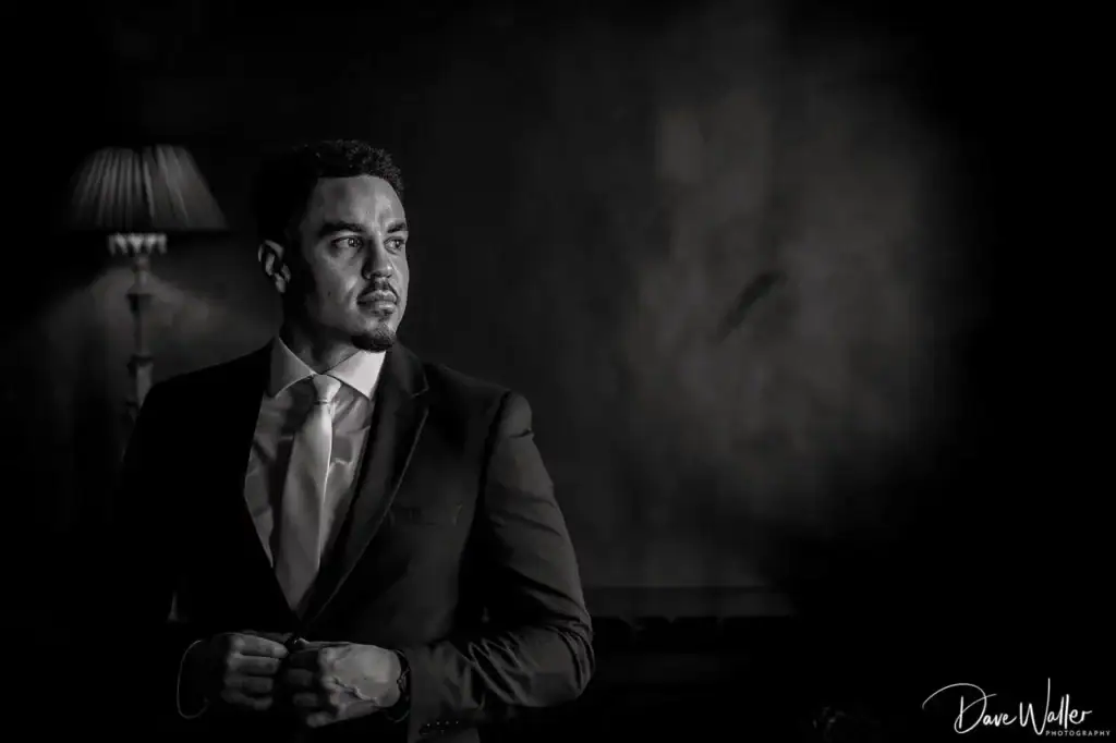 Man in suit, contemplative, lamp in background