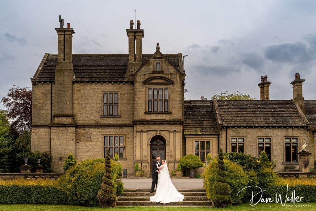 Bride and groom outside grand stone manor house