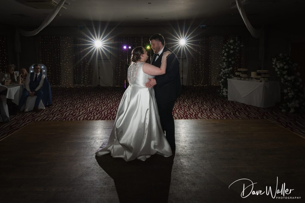 Bride and groom sharing first dance under lights