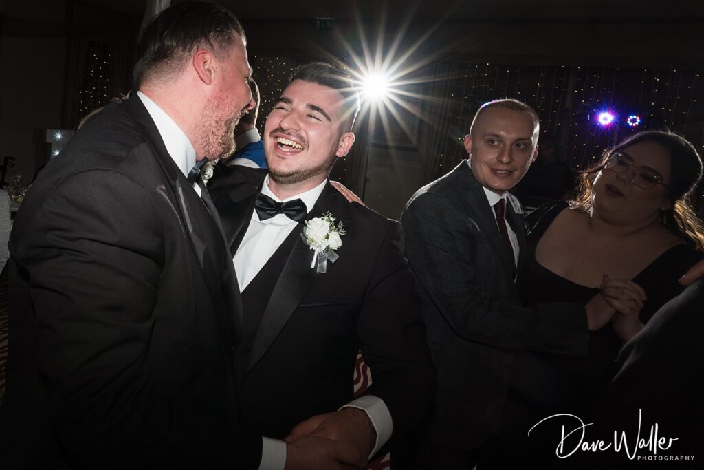 Groom laughing with guests at wedding reception
