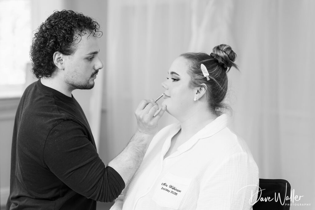 Make-up artist applying lipstick to seated woman
