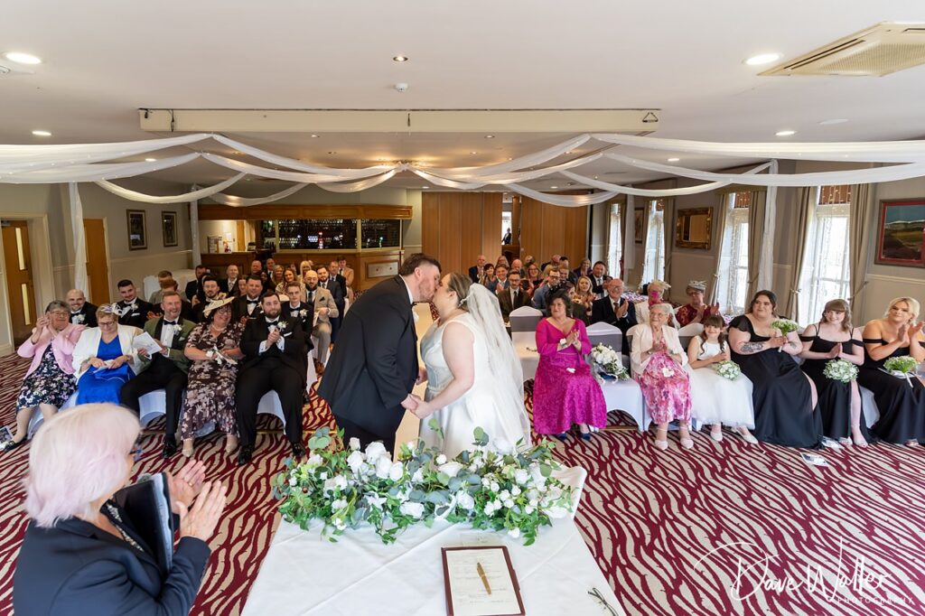 Bride and groom kissing during indoor wedding ceremony