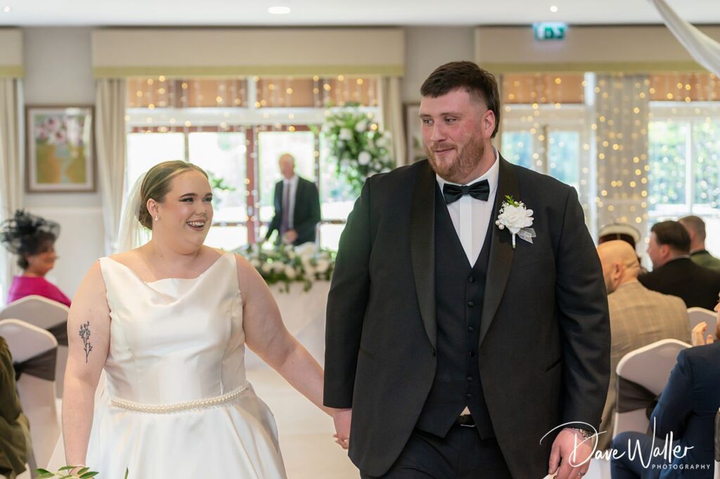 Bride and groom walking down wedding aisle indoors