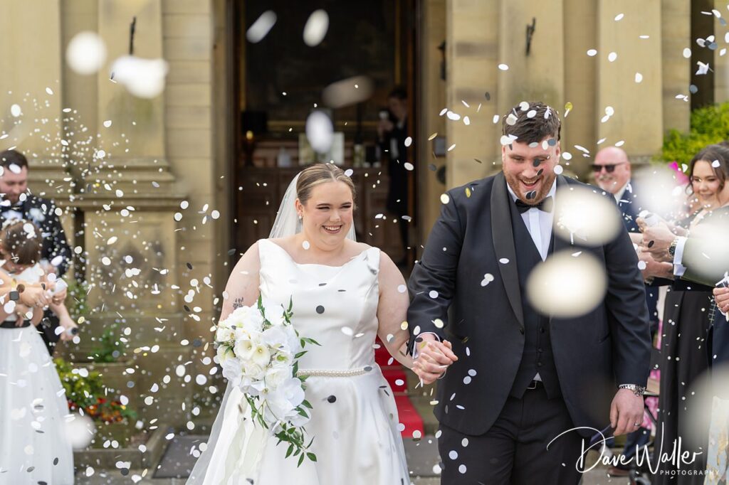 Bride and groom walking through confetti outside church
