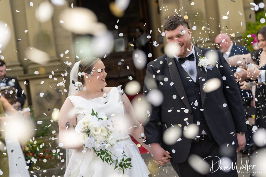 Bride and groom walking through falling confetti
