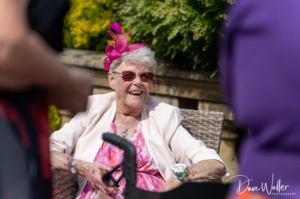 Smiling elderly woman in pink fascinator outdoors