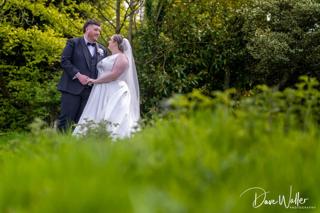 Bride and groom standing in lush garden
