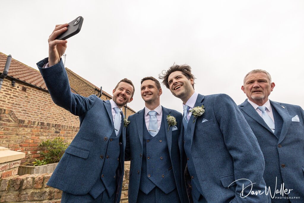 Groomsmen taking a selfie in blue suits.