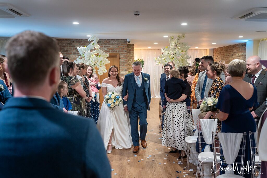 Bride walks down aisle with wedding guests.