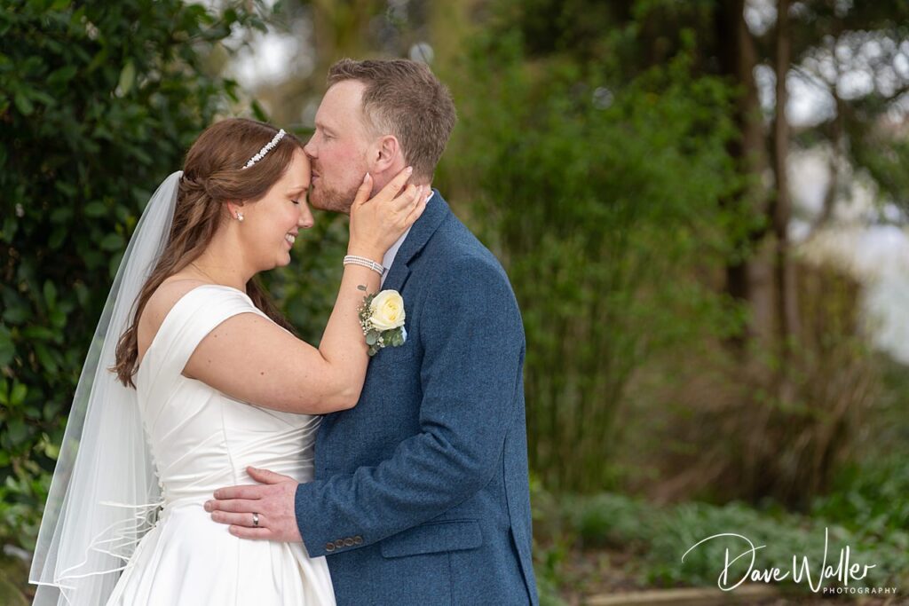 Bride and groom share intimate moment outdoors.