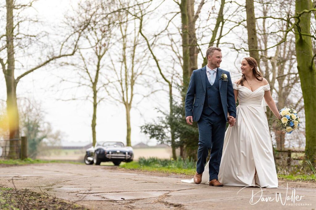 Bride and groom walking in countryside setting.