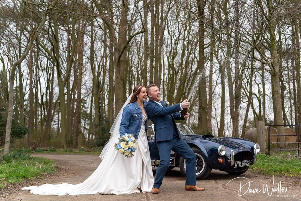Happy couple celebrating with champagne in woodland setting.