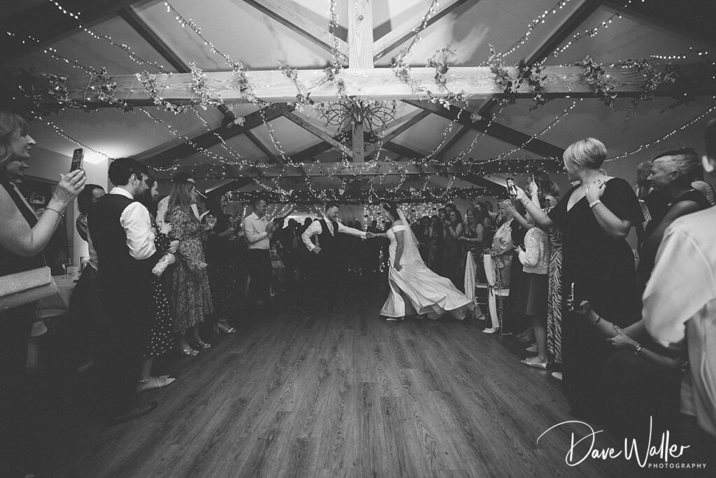 Wedding dance in decorated venue with guests applauding.
