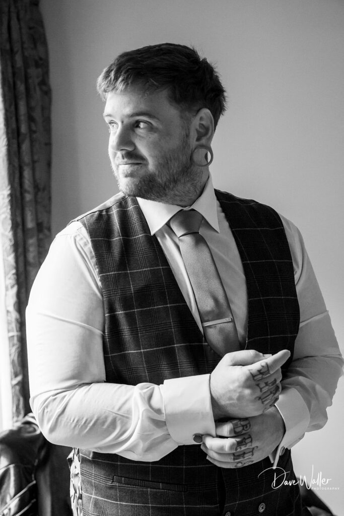 Tattooed man in suit adjusting his sleeves