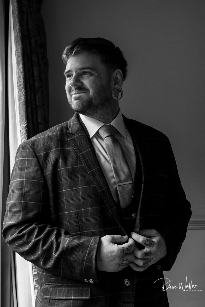 Man in suit gazing out window, monochrome portrait.