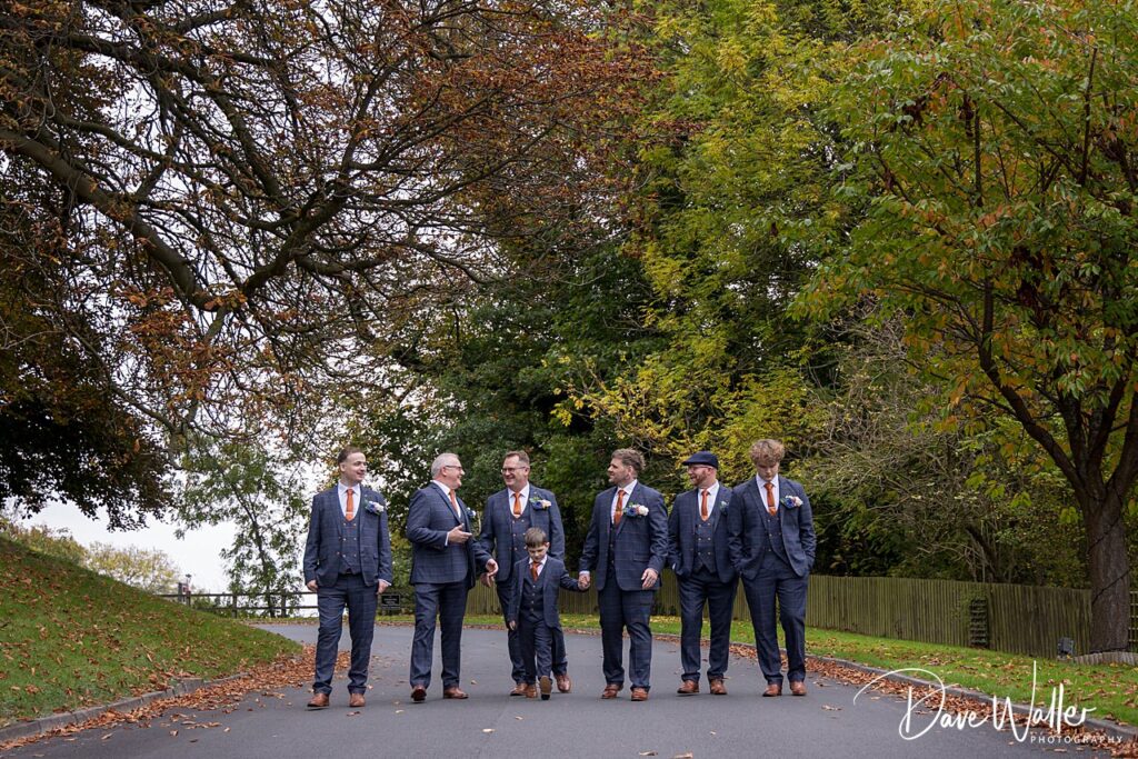 Groom and groomsmen walking together outdoors in suits.