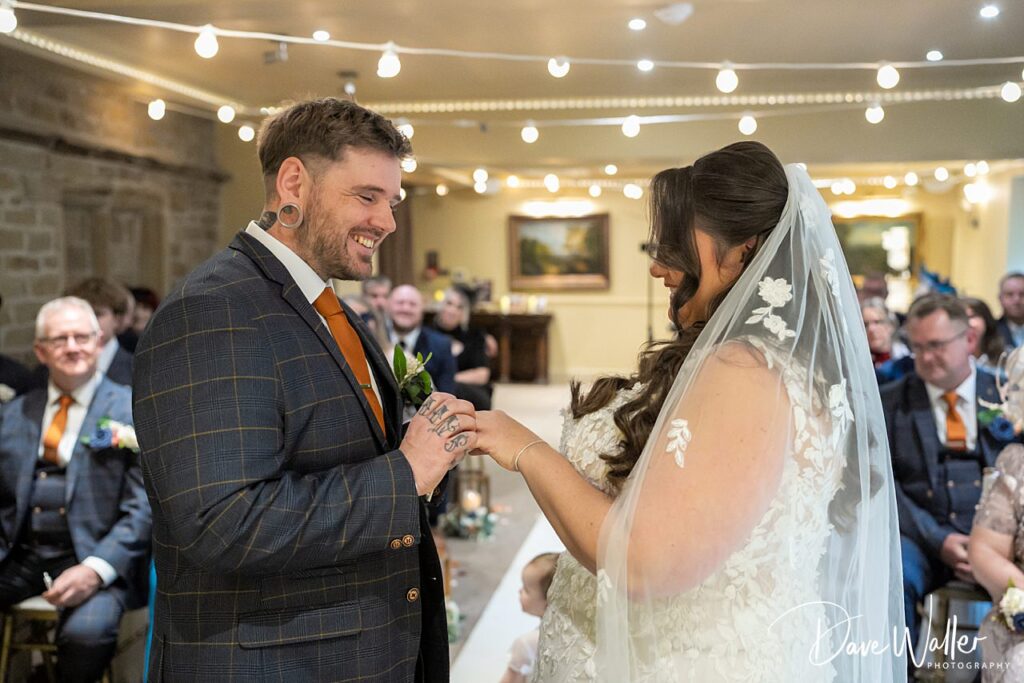 Bride and groom exchange rings during wedding ceremony.