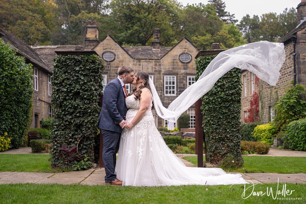 Bride and groom kiss in garden setting.