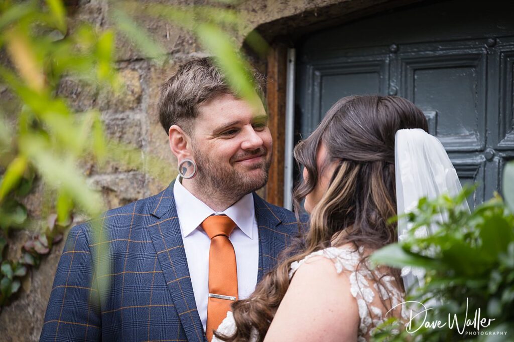 Wedding couple smiles lovingly at each other outdoors.