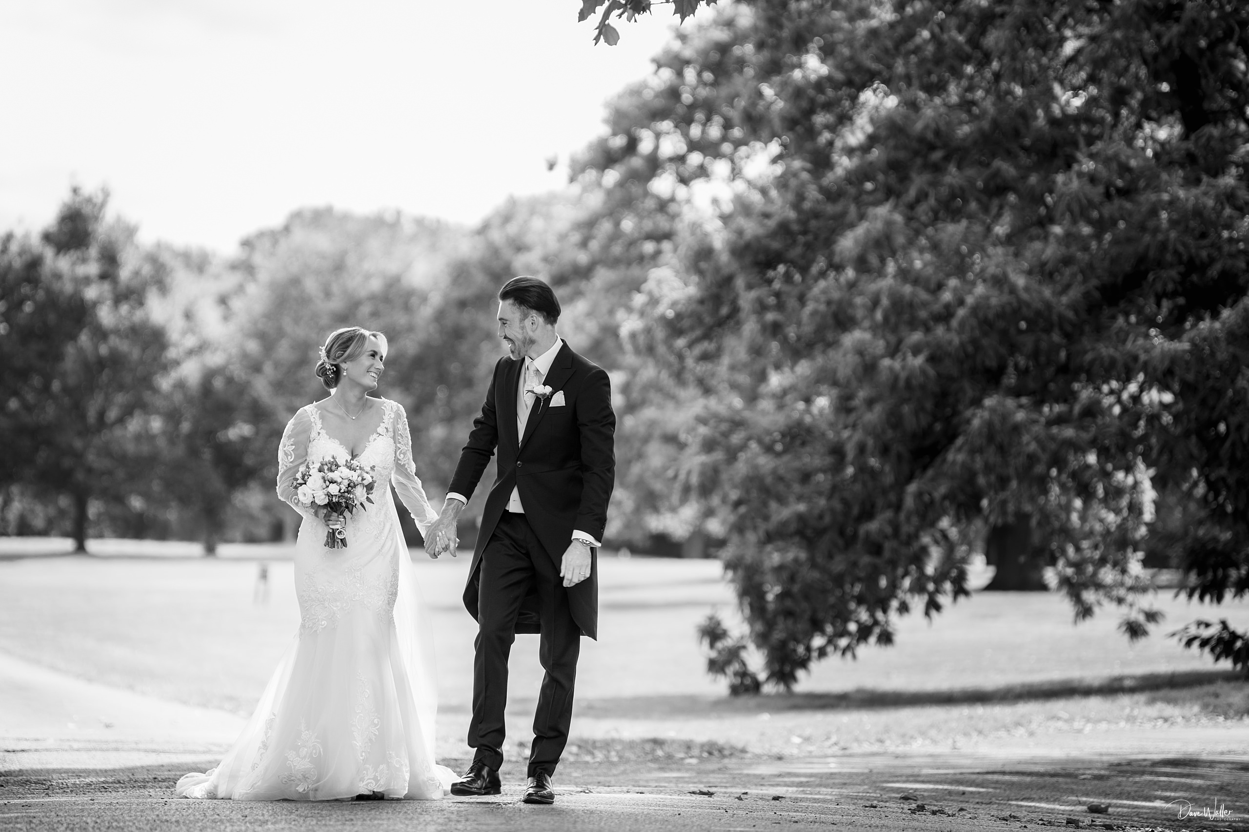 Bride and groom walking in a park.