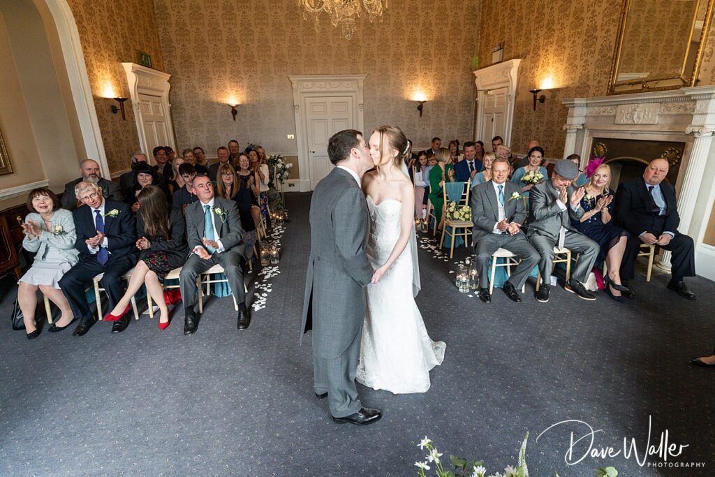 Newlyweds kiss in elegant wedding ceremony room.