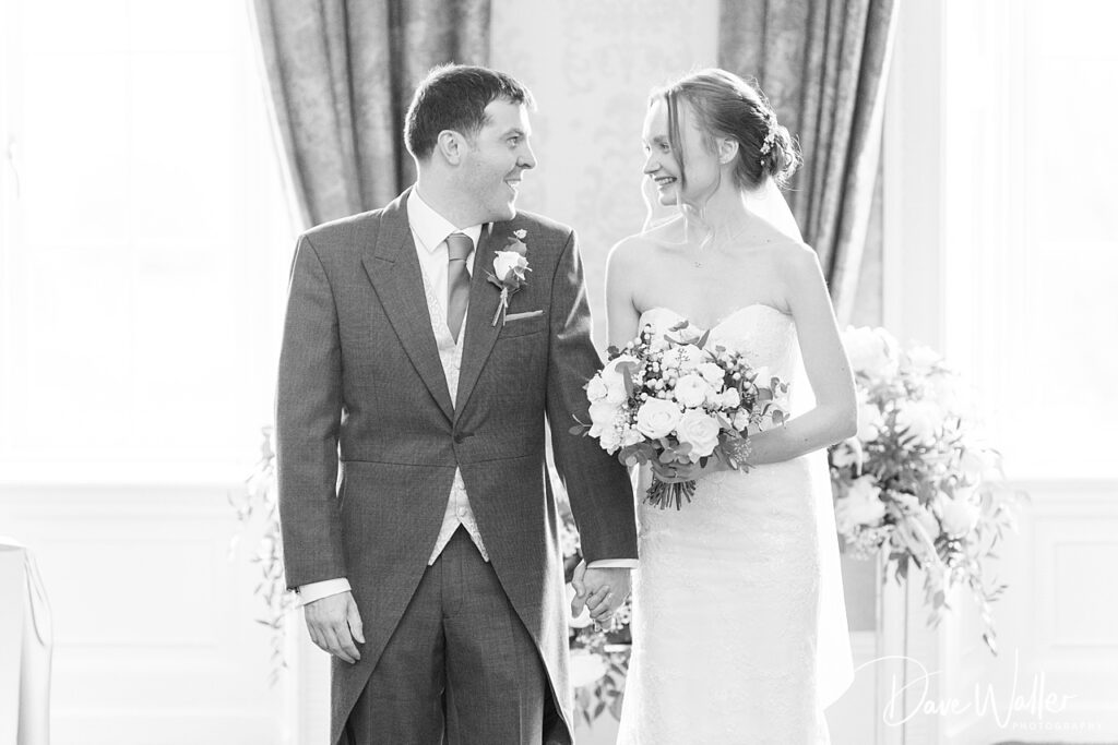 Bride and groom smiling, holding hands, wedding ceremony.