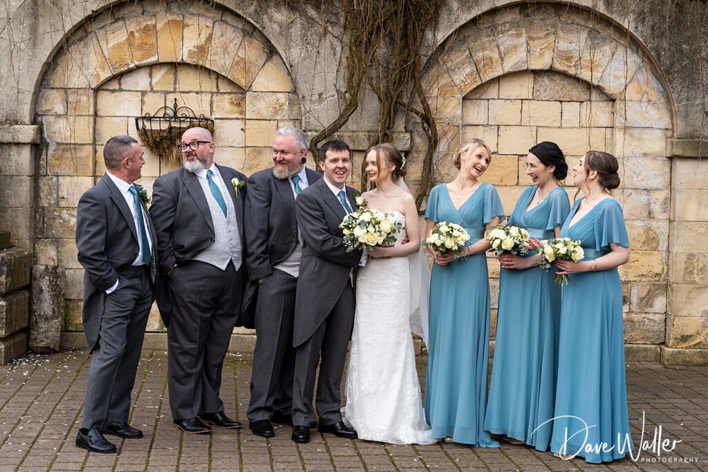 Wedding party posing in courtyard, smiling and laughing.