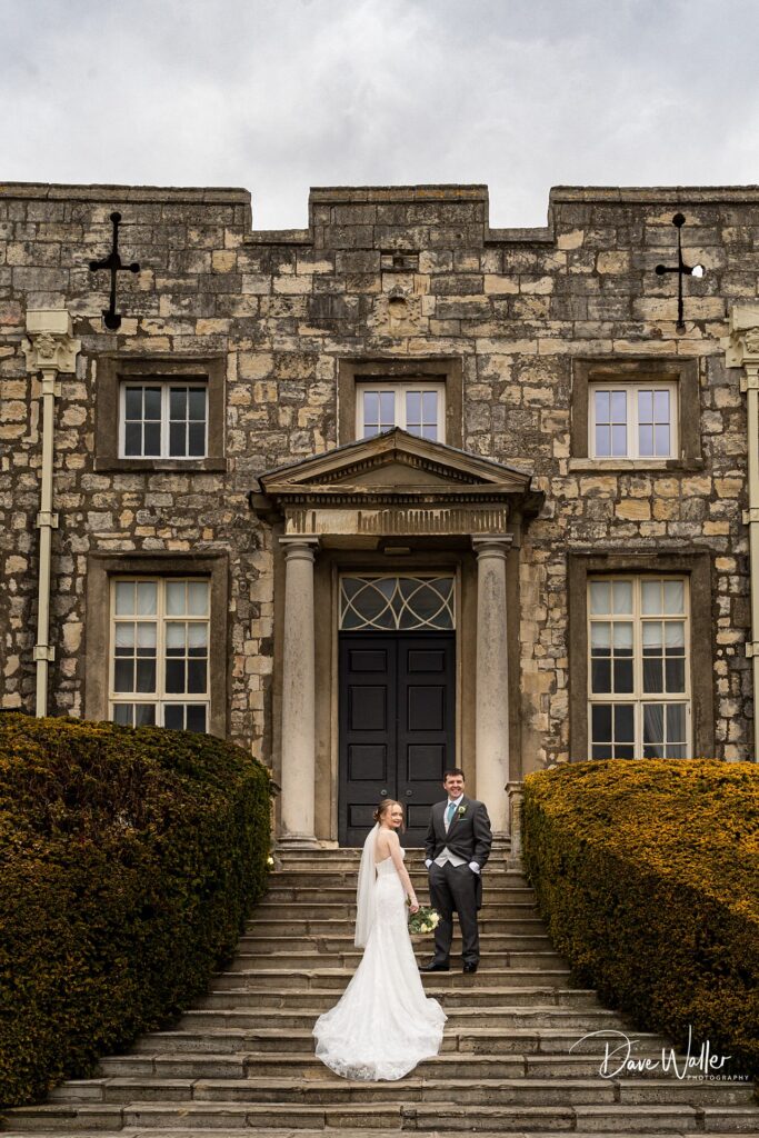 Bride and groom on historic building steps.