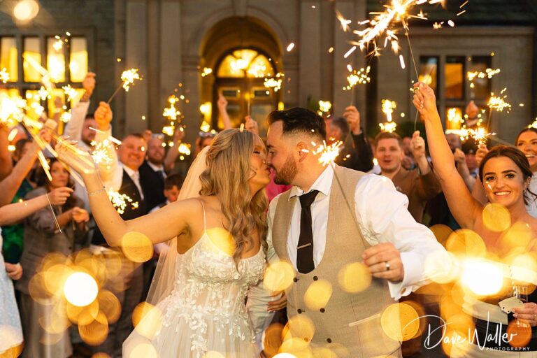 Bride and groom kissing with sparklers celebration.