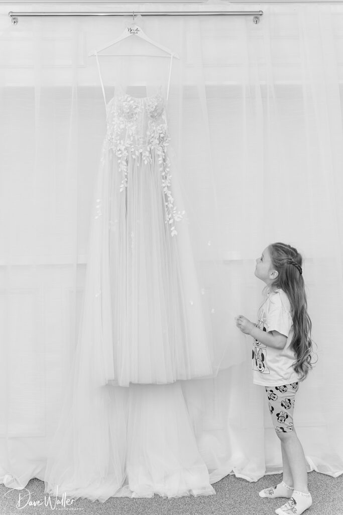 Child gazes at hanging wedding dress