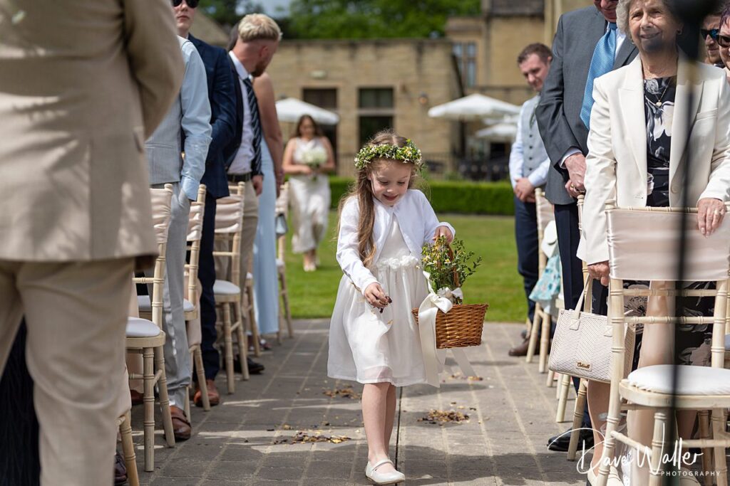 Flower girl walking down wedding aisle outside