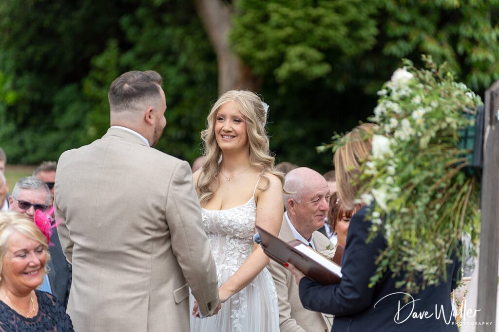 Bride and groom exchanging vows at outdoor wedding.