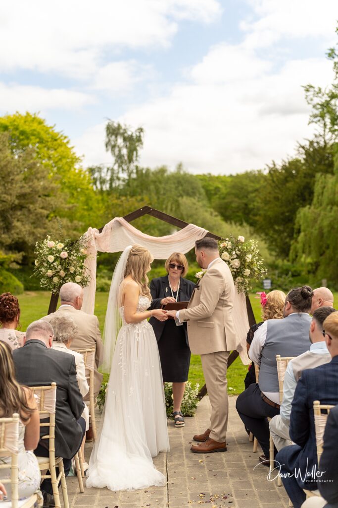 Outdoor wedding ceremony with bride and groom exchanging vows.